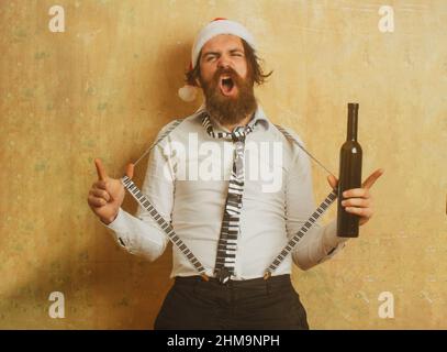 Funny crazy santa. Drunk bad santa holding bottle of whiskey or wine. Stock Photo