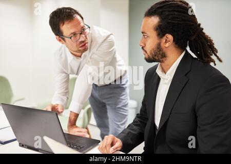 Two business people as programmers discuss software development on the laptop PC in the office Stock Photo