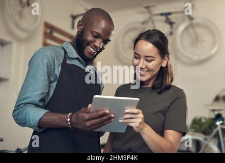 Can you help me find this bike. Shot of two young colleagues standing together in their bicycle shop and using a digital tablet. Stock Photo