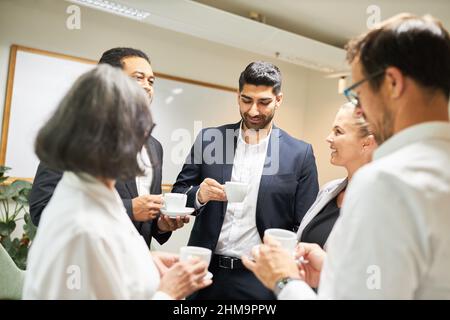 Group of business people having a coffee break after the meeting having relaxed small talk in the office Stock Photo