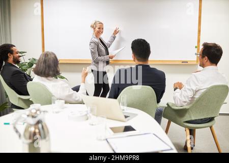 Young business woman giving a presentation on the whiteboard in front of a start-up team in the conference room Stock Photo