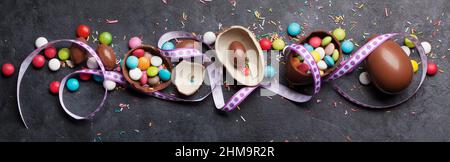Easter greeting card with chocolate eggs and colorful candies. Top view flat lay Stock Photo