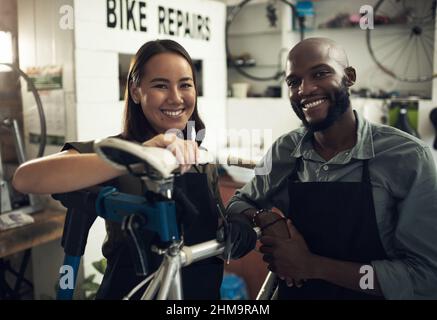 We put your bike first in here. Shot of two young business owners standing together in their bicycle shop during the day. Stock Photo