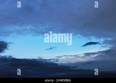 Area of blue sky surrounded by dark clouds Stock Photo