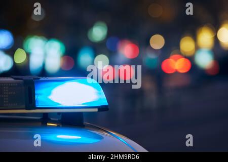 Blue flasher light of siren of police car at night city street. Themes crime, emergency and help. Stock Photo