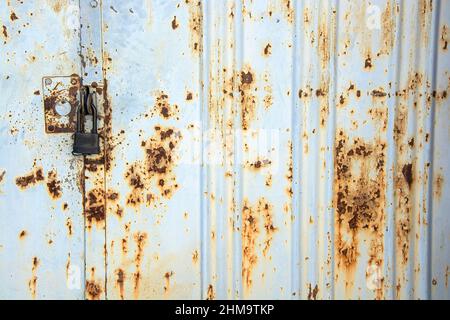Old rusty metal gate with a new black lock. Stock Photo