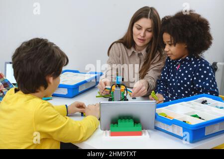 Multiethnic kids at STEM lesson constructing robot in classroom with ...