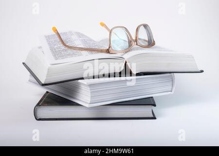 Glasses at books stack. Education, preparing for exams, information search concept. Books, codes or novels on grey background. High quality photo Stock Photo
