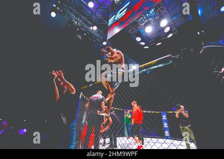 Zrenjanin, Vojvodina, Serbia October 16, 2021: MMA XXXVI SBC Tournament. Professional MMA fighter is sitting on the wire fence of the ring with folded Stock Photo