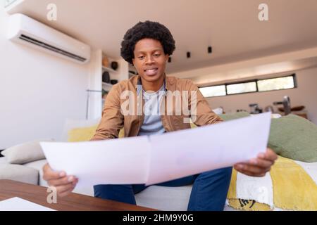 Smiling african american young businessman reading documents while working at home Stock Photo