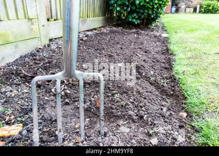 Digging fork in garden with hand gloves Stock Photo