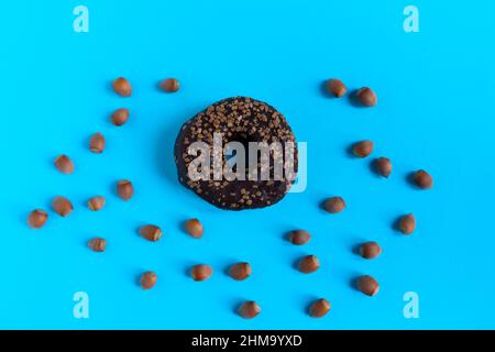 Donut with hazelnuts on a blue background, close up Stock Photo
