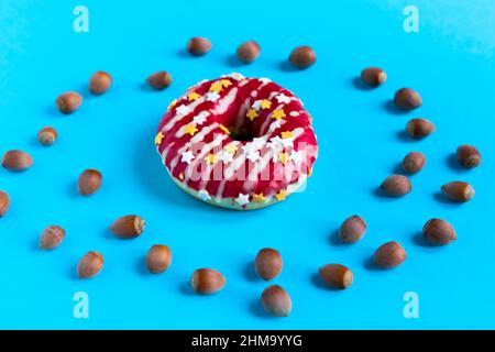 Donut with hazelnuts on a blue background, close up Stock Photo