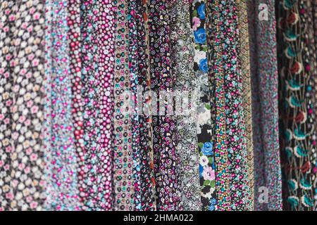Large rows of pieces of fabric made of cotton, polyester, and other materials in different colors and prints of clothing, soft focus Stock Photo