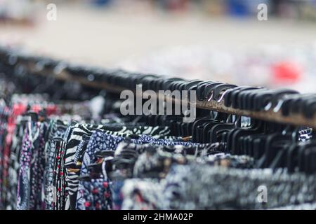 Large rows of pieces of fabric made of cotton, polyester, and other materials in different colors and prints of clothes, pants on a hanger in a store, Stock Photo