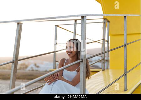 Happy African American male in undershirt with modern haircut looking at camera against building in sunlight Stock Photo