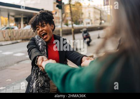 Overjoyed African American female screaming with opened mouth while meeting with crop girlfriend on city street Stock Photo