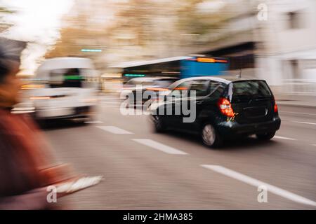 Defocused cars and bus driving on asphalt road near unrecognizable pedestrian in autumn city Stock Photo