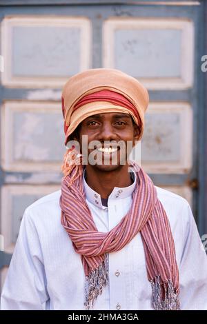 Cheerful elderly male medic in uniform holding folder standing in hospital while talking on mobile phone Stock Photo