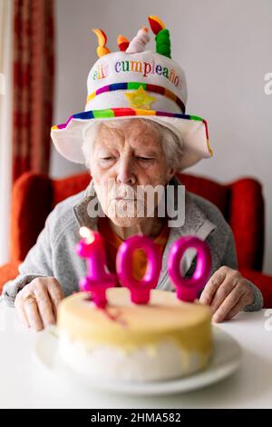 Free Photo | Surprised elderly woman wearing party hat holds birthday cake  blowing whistle looking at side on green