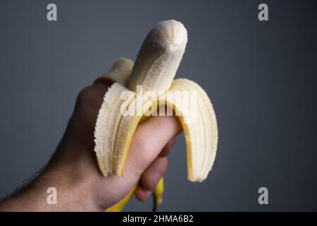 A peeled yellow banana in a human hand is being eaten Stock Photo