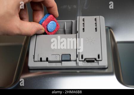 A person inserting a dishwasher tab into the dishwasher Stock Photo