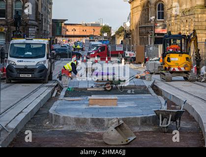 Leith, Edinburgh, Scotland, United Kingdom, 8th February 2022. Trams to Newhaven construction: As the major project approaches its final year, with work due on schedule and due to be completed in Spring 2023 within its £207.3m budget, numerous roads are closed to traffic in Leith. More than 60% of track has now been laid (2.8km) & 85% of the utility diversions have been carried out. Pictured: workers building a platform tram stop  on Constitution Street Stock Photo