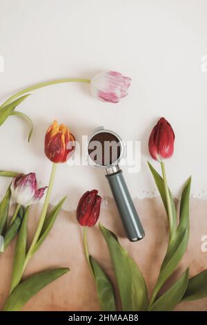 Fresh tulips and metal holder from the coffee machine with ground coffee inside. Coffee horn and flowers Stock Photo
