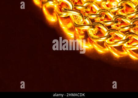Golden chain. Detail of a yellow iron chain. Metal chain link on the gold background. Decorative jewelry. Luxury design brilliant jewelry. Macro photo Stock Photo