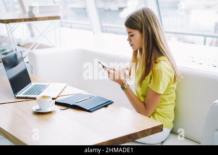 Young woman sending message using mobile phone in office lounge Stock Photo