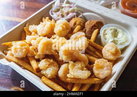 A plate of deep fried shrimp with fries and hush puppies Stock Photo