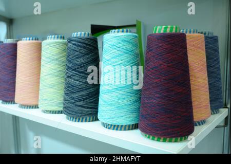 Colorful knitted thread spools put on a shelf at a shop. Stock Photo