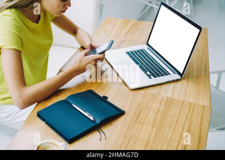 Anonymous woman working on laptop and smartphone with notepad Stock Photo