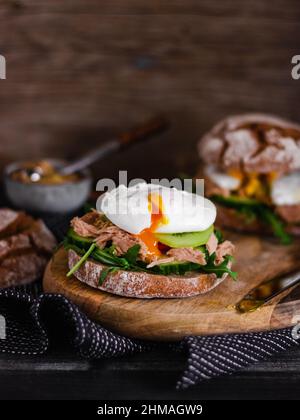 Poached egg on a full grain bun with avocado, cucumber, kiwi and arugula on a gray plate. Healthy breakfast. Brunch idea. Clean eating. vegetarian. pr Stock Photo