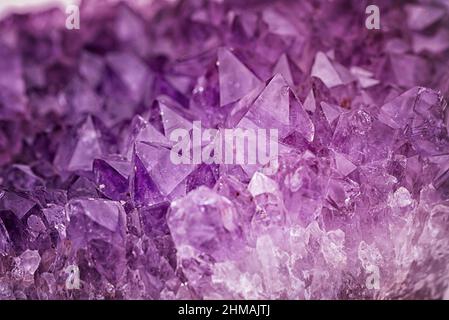 Close up purple shining amethyst quartz crystal texture abstract background Stock Photo