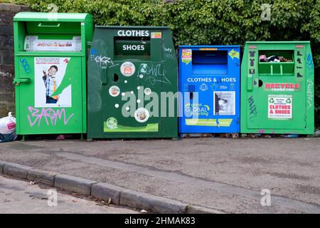 A row of roadside metal  bins which are designated for charitable shoe, textile and clothing donations for recycling. Operated by the local council Stock Photo