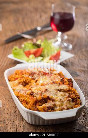 gratinated pasta with salad on wood Stock Photo