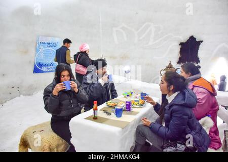 Gulmarg, India. 08th Feb, 2022. Indian tourists enjoy tea at the cafe. An igloo cafe, claimed to be the world's largest, has come up at the famous ski-resort of Gulmarg in Jammu and Kashmir. With a height of 37.5 feet and a diameter of 44.5 feet, Wasim, creator of the igloo, claimed it was the world's largest cafe of its kind. It took 64 days to complete it with 25 people working day and night, Mr Wasim said, adding that it took 1,700 man-days to complete the project. (Photo by Saqib Majeed/SOPA Images/Sipa USA) Credit: Sipa USA/Alamy Live News Stock Photo