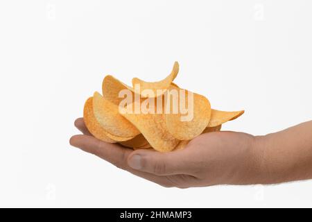 A human hand holds potato chips. It is isolated over white background. Close-up. Stock Photo