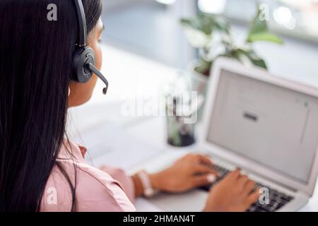 If theres a problem, well a.find a the solution. Shot of a businesswoman wearing a headset while working on her laptop. Stock Photo