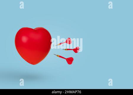 Dart arrows hitting in a red heart, isolated on a bright blue background. Minimal love and Valentines day concept. Copy space. Stock Photo