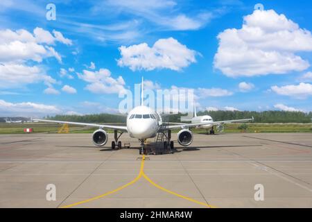 Airplane parked in good weather at the airport, straight view Stock Photo