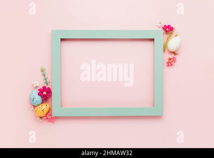 Easter holiday pink mockup background. Top view from above to different colorful Easter eggs, flowers, picture frame border. Card with copy space to place text. Minimal flat lay. High quality photo Stock Photo