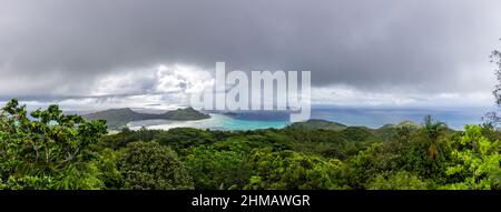 Panorama of Praslin Island with La Digue Island on the horizon, with tropical rainforest around, azure ocean, clouds and rain in the distance. Stock Photo