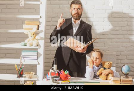 Serious teacher with a sad tired little student girl at the elementary school. Fathers and daughters learning. Doing homework with dad. Father support Stock Photo