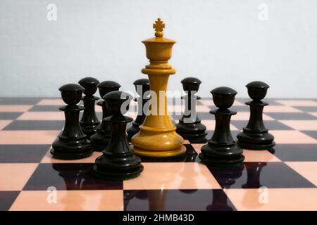 White chess king surrounded by black pawns Stock Photo