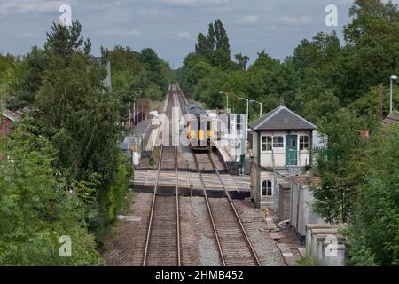 East Midlands trains class 156 sprinter train 156405 at Lowdham railway station (East of Nottingham)  with the level crossing and closed signal box Stock Photo