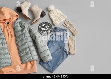Paper with text BLACK FRIDAY SALE, warm female clothes, accessories and shoes on grey background Stock Photo