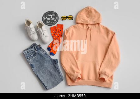 Paper with text BLACK FRIDAY SALE, female clothes, accessories and sneakers on light background Stock Photo