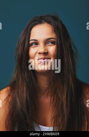 Messy hair, meaningful life. Studio shot of a beautiful young woman posing  against a blue background Stock Photo - Alamy